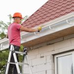 worker installs the gutter system on the roof