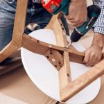 The man handyman is engaged in assembling the chair. The repairman is engaged in mending the chair.